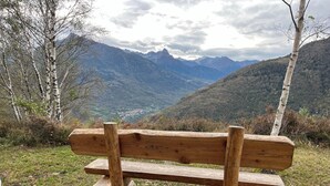 A wooden bench with a view of a valley and mountains in the background. - Sorriso Berzo Apartment With Stunning Views (Berzo Demo)
