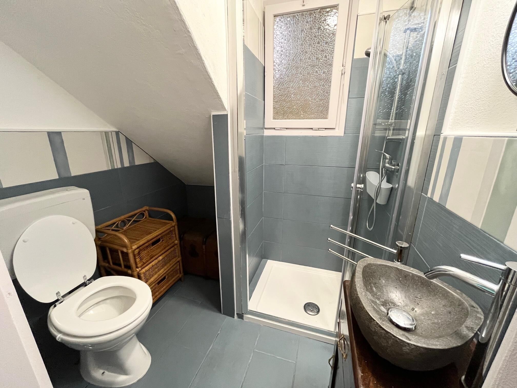 A compact bathroom with a toilet, a shower stall, and a sink.