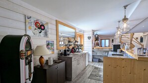 A kitchen with wooden cabinets, a jukebox, and a large mirror. - Spacious family chalet with spa, sauna and games room (Ban-sur-Meurthe-Clefcy)