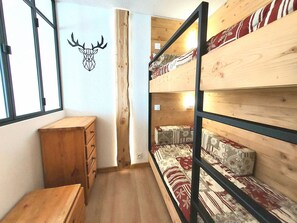 A wooden bunk bed room with a wooden dresser and a wall-mounted deer head decoration.