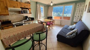 Une cuisine chaleureuse avec un coin repas, un canapé et une vue sur l’extérieur.