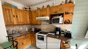 Une cuisine de taille réduite, dotée de meubles en bois, d’un four à micro-ondes, d’une cuisinière et d’un réfrigérateur.