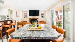 Un comedor moderno con una mesa de mármol, sillas anaranjadas y una chimenea.