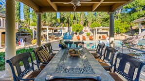 Un espacio de comedor al aire libre cubierto, con una piscina al fondo.
