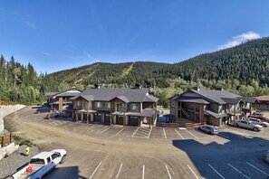 A hotel with multiple buildings, a parking lot, and a mountainous backdrop.