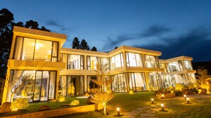 A modern two-story house with large glass windows, a well-maintained lawn, and outdoor lighting. - TKH Resort (Hoa Son)