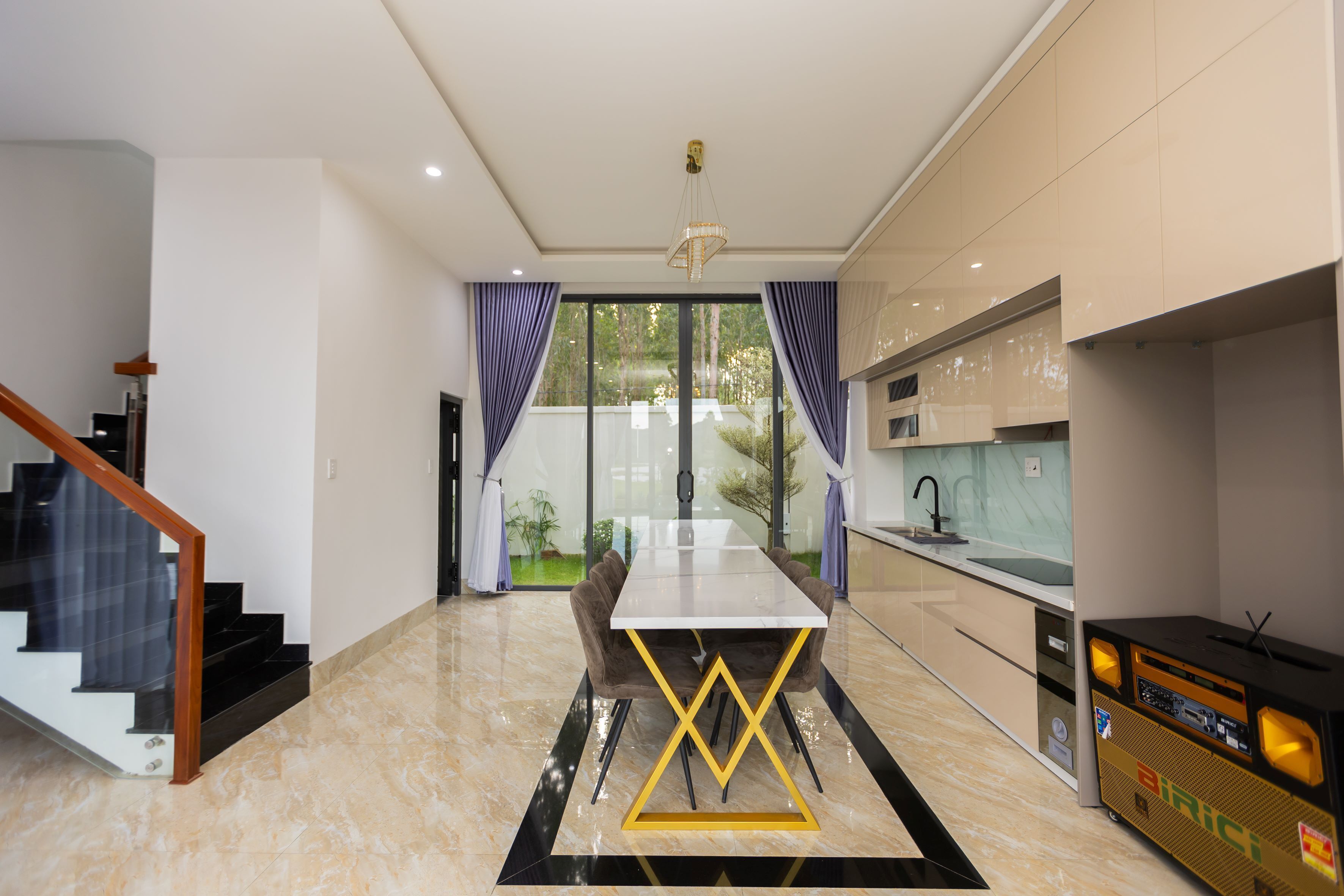 Una cocina moderna con comedor, una escalera y vistas al exterior.