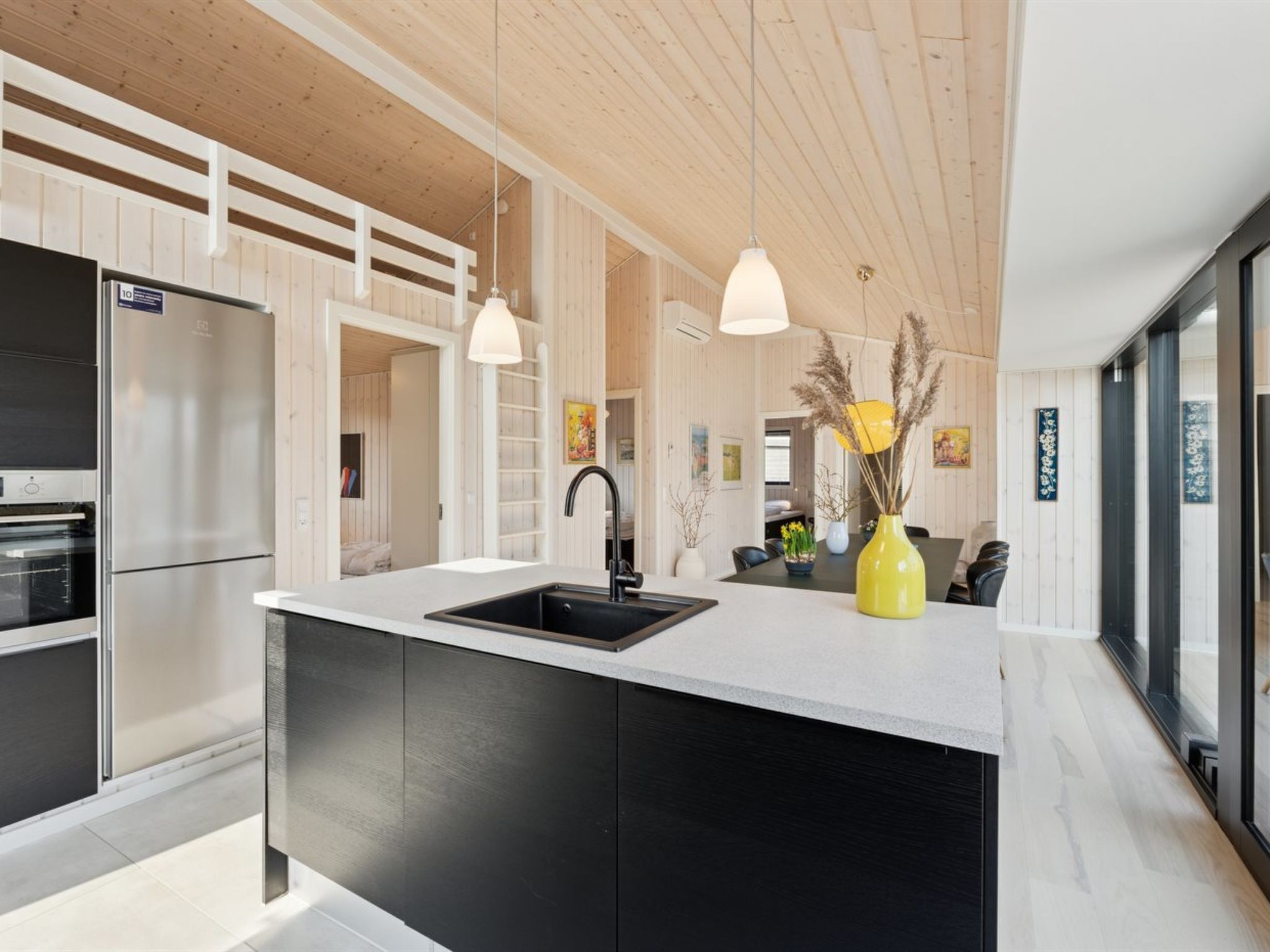 Una cocina moderna con una isla central, armarios negros y electrodomésticos de acero inoxidable.