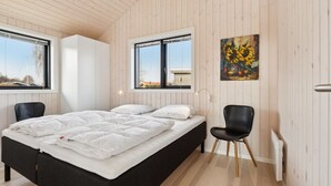 A bedroom with a large bed, two chairs, wooden walls, and a window. - "Viveke" - 10m from the sea by Interhome (Bjert)