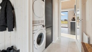 A laundry room with a washing machine and dryer, a coat rack, and a pair of shoes. - "Viveke" - 10m from the sea by Interhome (Bjert)