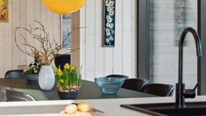 A modern kitchen with a white countertop, a yellow pendant light, a vase with daffodils, a blue glass bowl, and a black faucet. - "Viveke" - 10m from the sea by Interhome (Bjert)