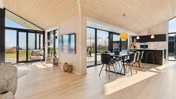 A spacious modern interior with a wooden ceiling, large windows, a dining area, and a kitchen. - "Viveke" - 10m from the sea by Interhome (Bjert)