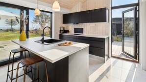 A modern kitchen with a large island, black cabinets, and pendant lighting. - "Viveke" - 10m from the sea by Interhome (Bjert)