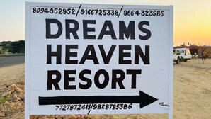 Un panneau indiquant le « Dreams Heaven Resort », avec les numéros de téléphone et une flèche pointant vers la droite.