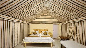 Une pièce avec un plafond en pente, un lit avec des oreillers, un banc et une petite table.
