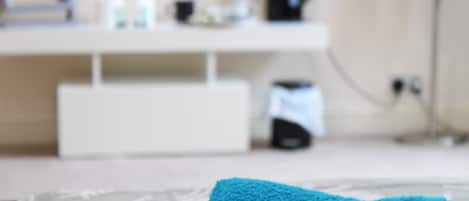 Un bagno con un lavandino bianco, una macchina da caffè nera e un asciugamano sul ripiano.