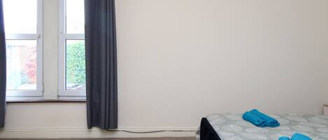 A room with a bed, a window with curtains, and a carpeted floor.