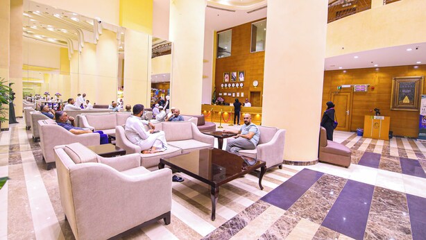 Um hall amplo com diversas áreas de estar, um balcão de recepção e um posto de check-in.
