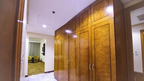 Um corredor com um guarda-roupa de madeira, piso de mármore e um sofá amarelo ao fundo.