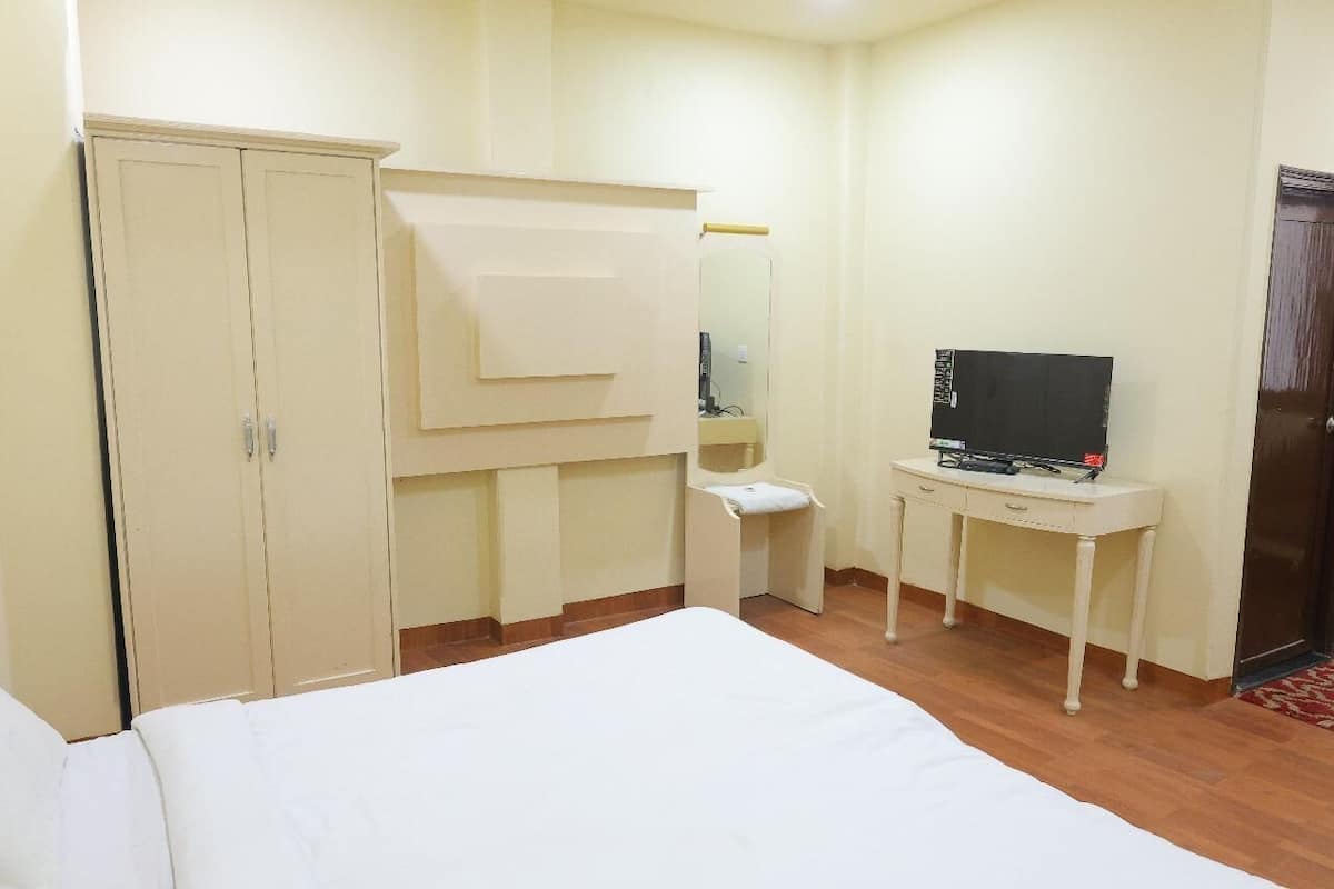 Hotelkamer met een bed, een kledingkast, een bureau met televisie en een spiegel.