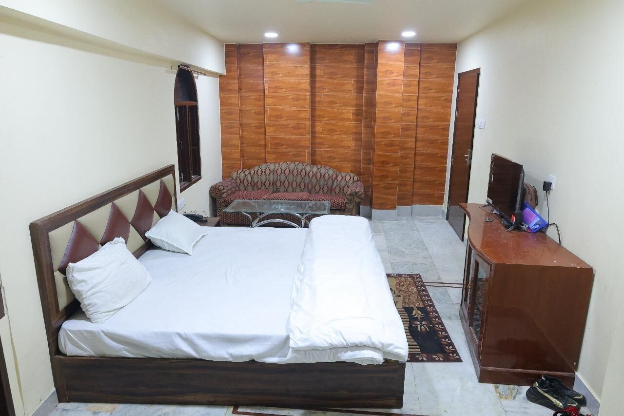 Un dormitorio con cama, sofá, televisor y escritorio.