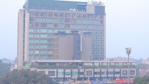 Een meerlaags hotel met een modern architectuurontwerp, met een opvallende ingang en een terras op het dak.