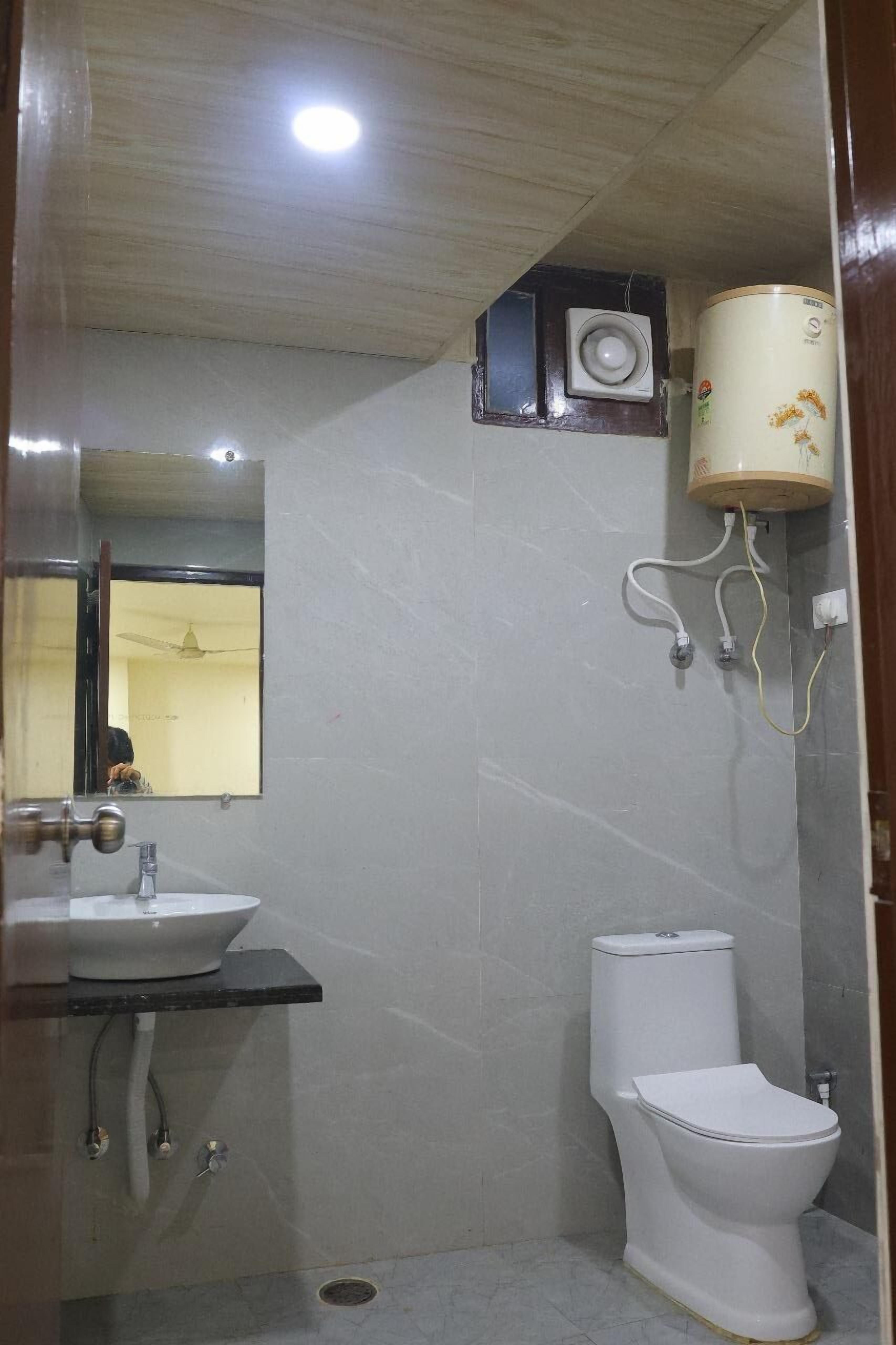 A bathroom with a white sink, toilet, and a ceiling fan.