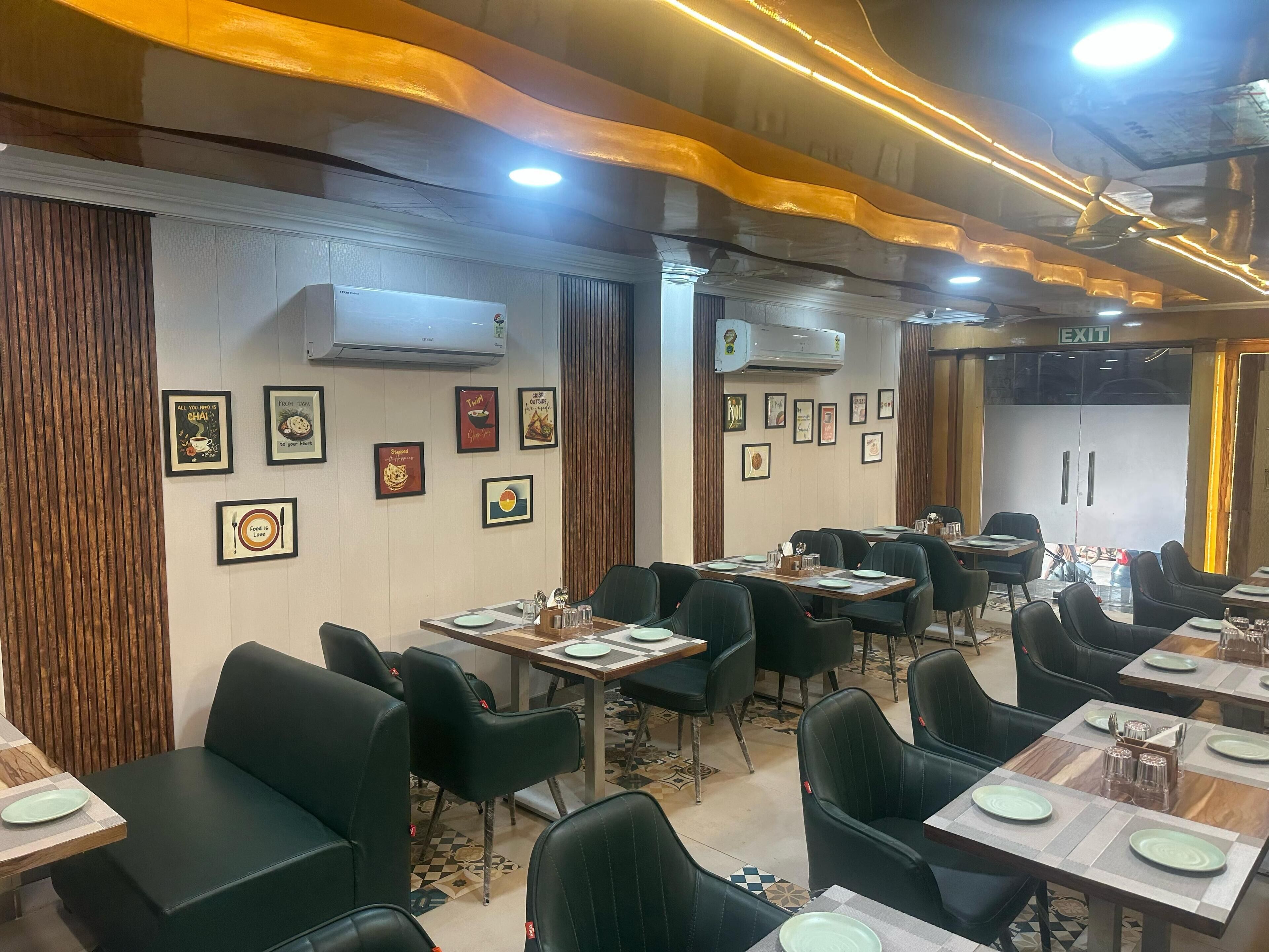A restaurant with tables and chairs, framed pictures on the walls, and an exit sign.