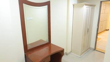 A room with a wooden vanity, a mirror, a white wardrobe, and a tiled floor.