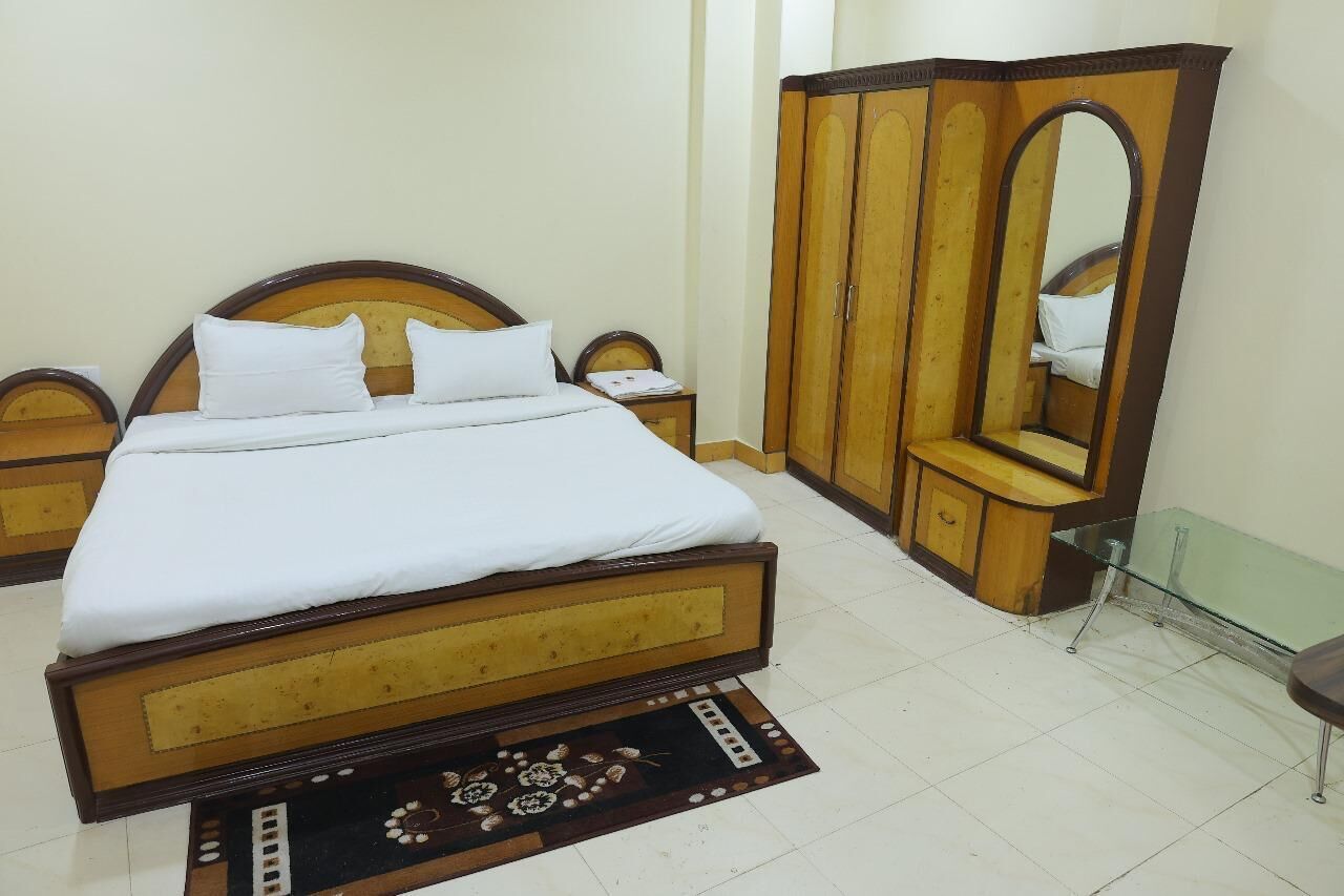 Un dormitorio con cama de madera, mesita de noche, armario y espejo.