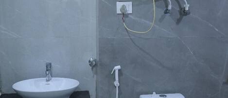Un baño con lavamanos blanco, inodoro y calentador de agua montado en la pared.