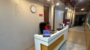 Een receptiebalie met een klok aan de muur, een computer en een bord met de naam van het hotel.