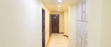 A narrow hallway with tiled flooring and a door at the end.