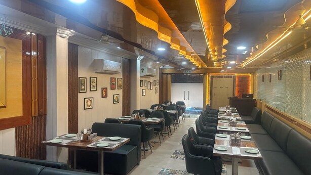 Een restaurant met meerdere eettafels en zitbanken, airconditioning en wanddecoraties met ingelijste foto's, plus een vloer met een patroon.