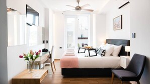 Une chambre à coucher moderne, comprenant un lit, une table de chevet, une chaise, un bureau et un ventilateur de plafond.
