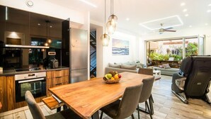 Une cuisine moderne avec une table et des chaises en bois, un panier de fruits et un coin repas comprenant un canapé et un fauteuil.