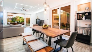 Une cuisine moderne avec une table à manger en bois, des appareils électroménagers intégrés et une vue sur le jardin.