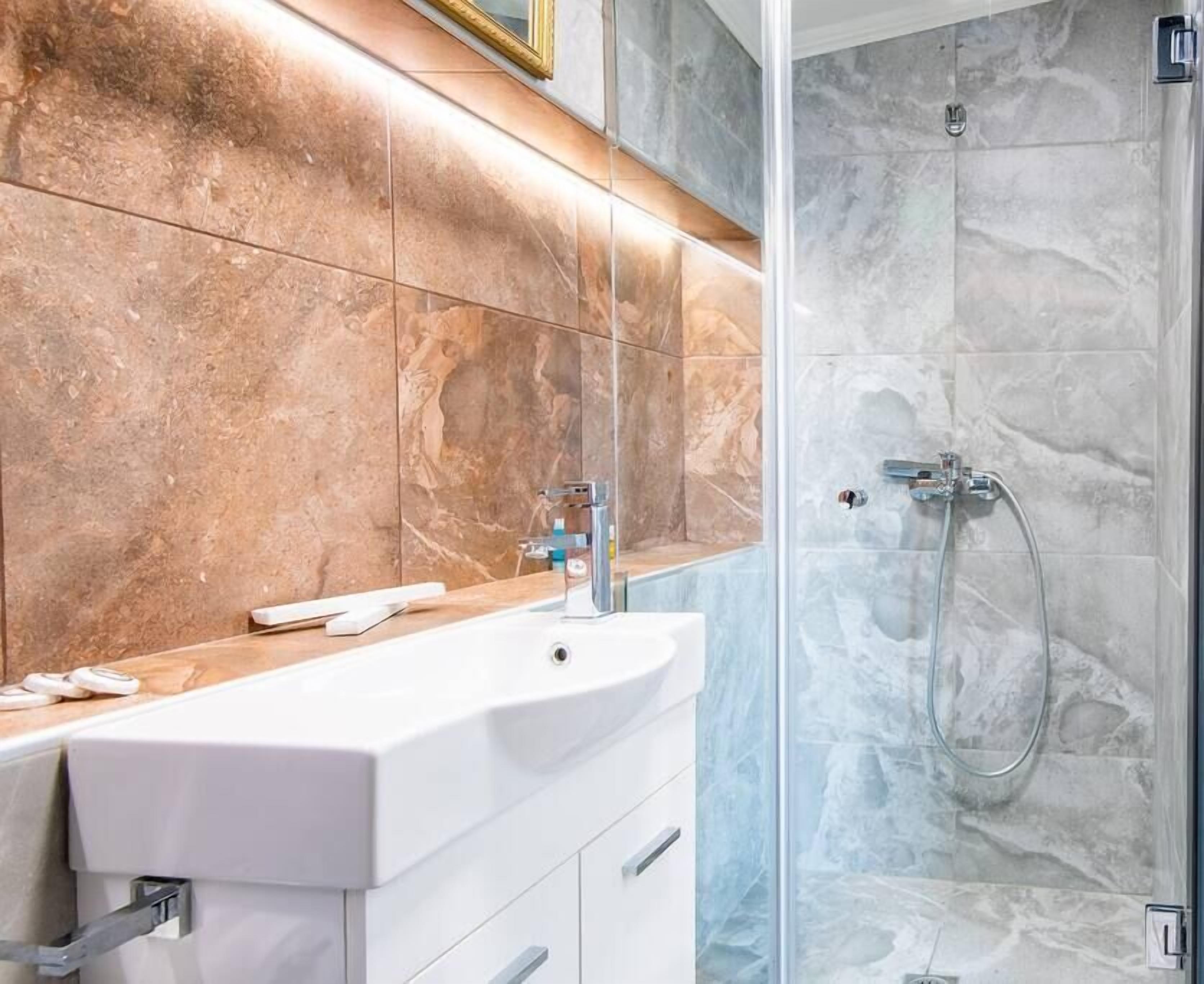 Een badkamer met een wit wastafelmeubel, een spiegel en een douche met een glazen deur.