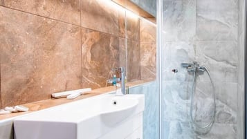 Een badkamer met een wit wastafelmeubel, een spiegel en een douche met een glazen deur.