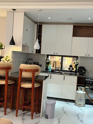 Enjoy cooking in this well-equipped kitchen with a stainless steel stove, white cabinetry, and a black countertop.