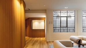 A modern interior with wooden paneling, a wooden floor, a sofa, and a window with decorative glass. - Colectia Stays Gran Vía (Madrid)