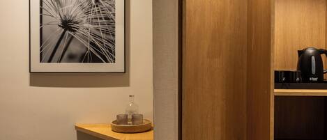 A modern bathroom with a wooden vanity, a framed photograph on the wall, and a coffee maker on the shelf.