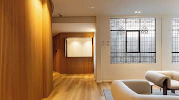 Un interior moderno con paneles de madera, suelo de madera, un sofá y una ventana con vidrio decorativo.