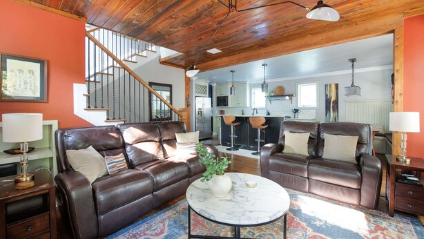A spacious living room with leather sofas, a marble coffee table, and a staircase leading to an upper level. - Silver Stallion (Atlanta)