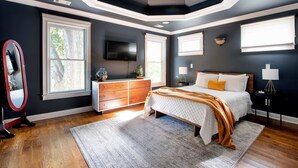A bedroom with a bed, dresser, TV, and windows. - Silver Stallion (Atlanta)