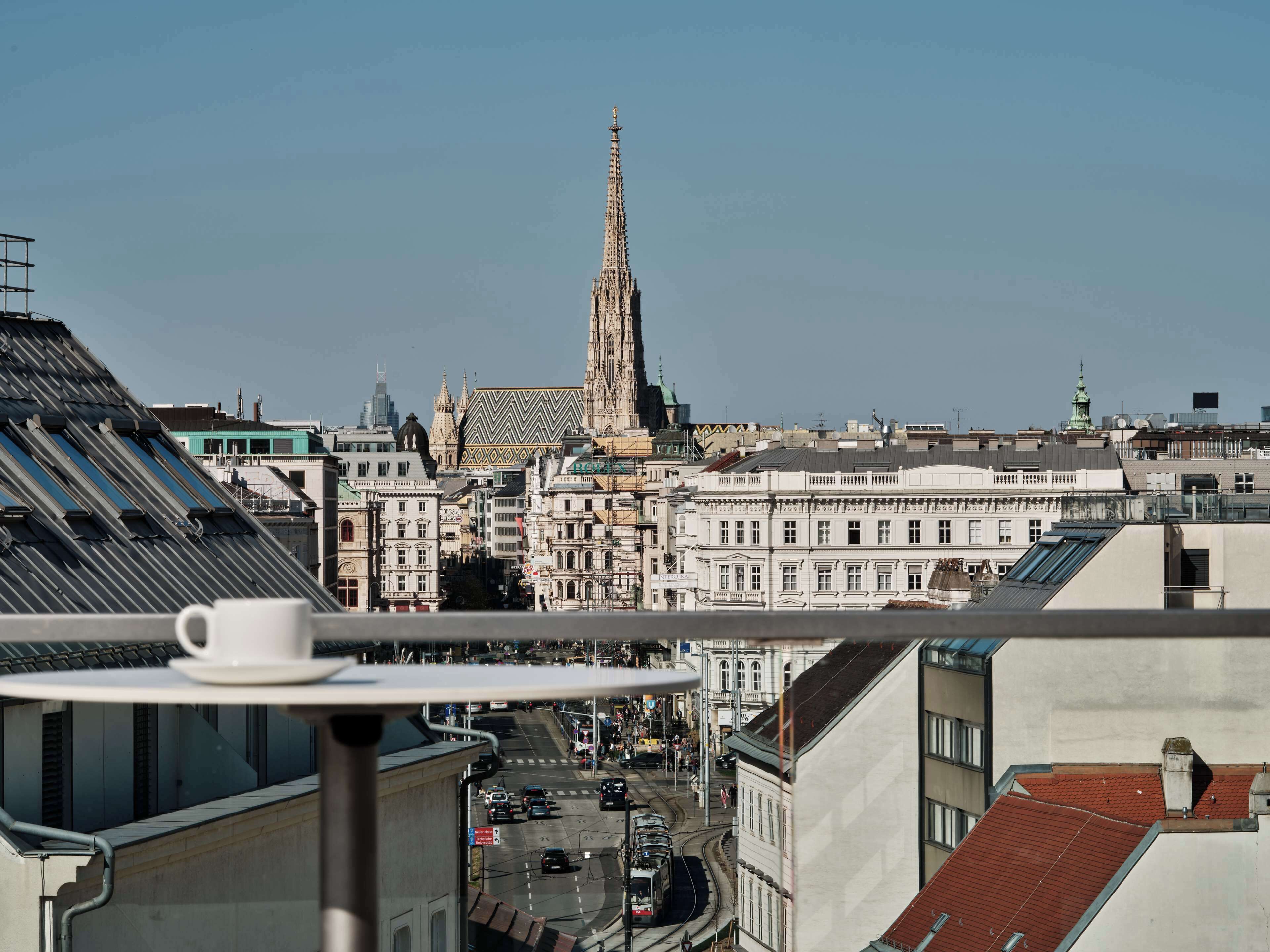 A cityscape with a prominent church spire, modern buildings, and a tram line.