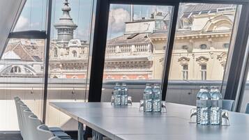 Un salón de conferencias con una mesa lista para reuniones, amplias ventanas que ofrecen vistas de arquitectura histórica.