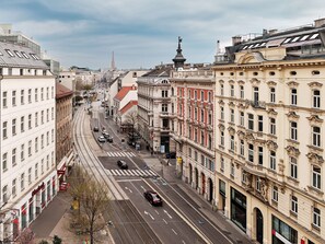 Vista de una calle en una ciudad con edificios históricos, una línea de tranvía y cielo despejado.