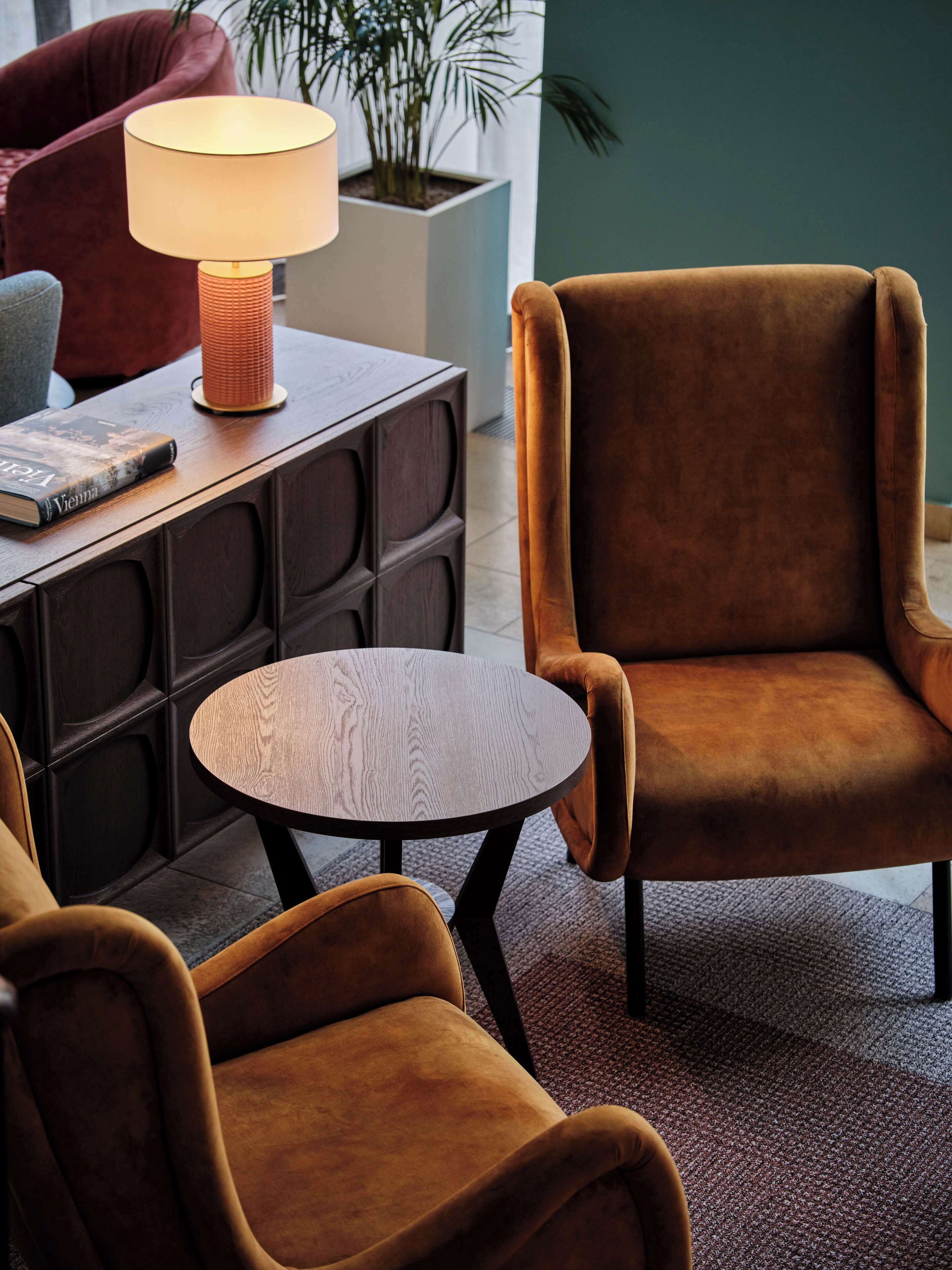 Un'area salotto accogliente con un tavolino rotondo, una poltrona confortevole e un comodino con una lampada e un libro.