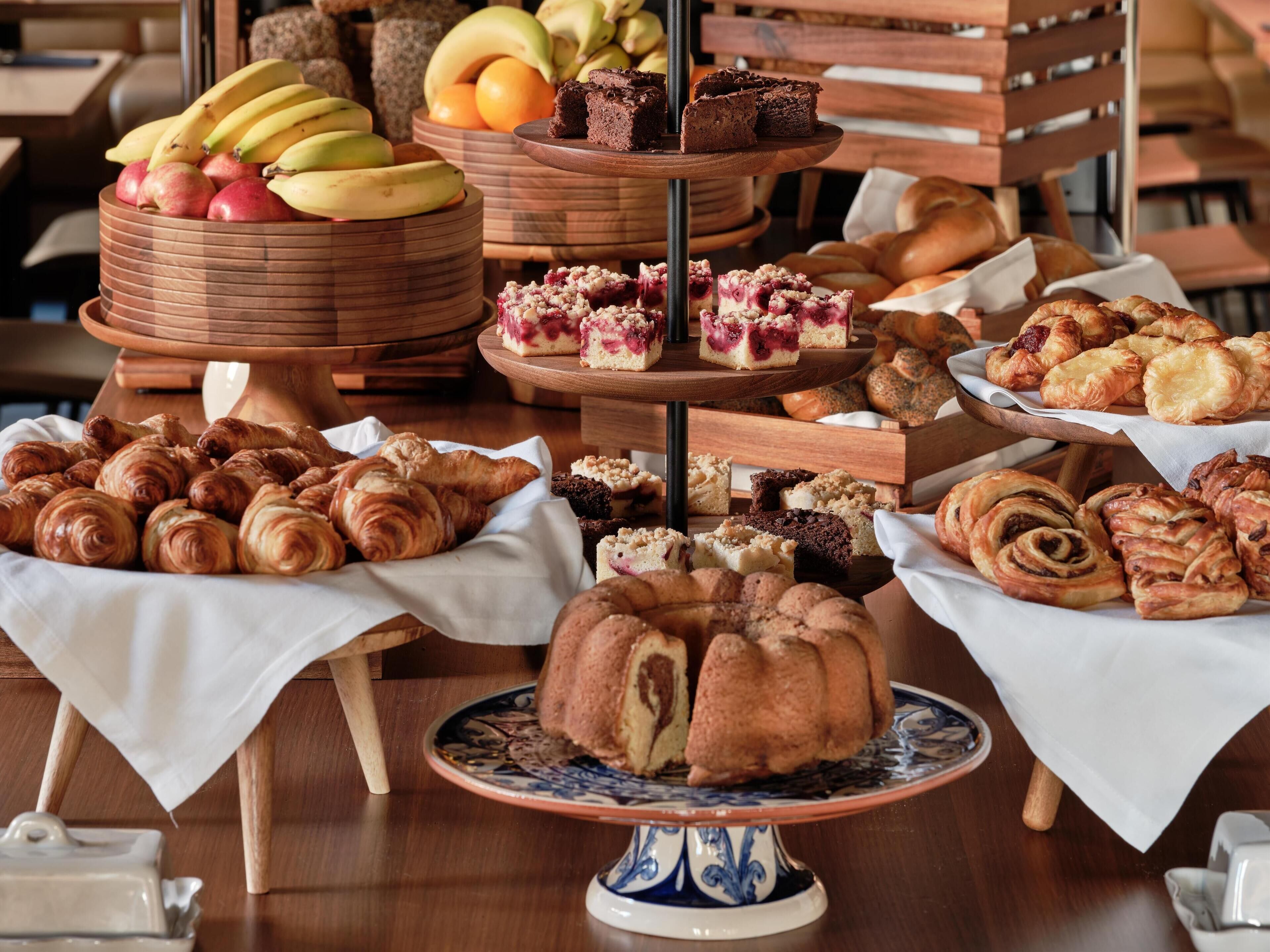 A buffet with various baked goods, including pastries, breads, and desserts.